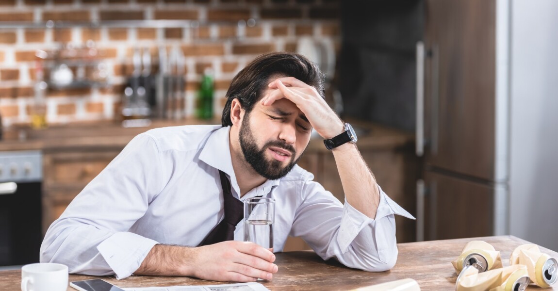 loner businessman having headache and hangover at kitchen